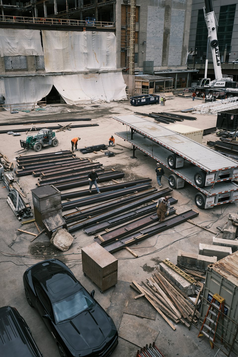 Trabajadores de la construcción organizan vigas de acero en una obra de construcción concurrida.