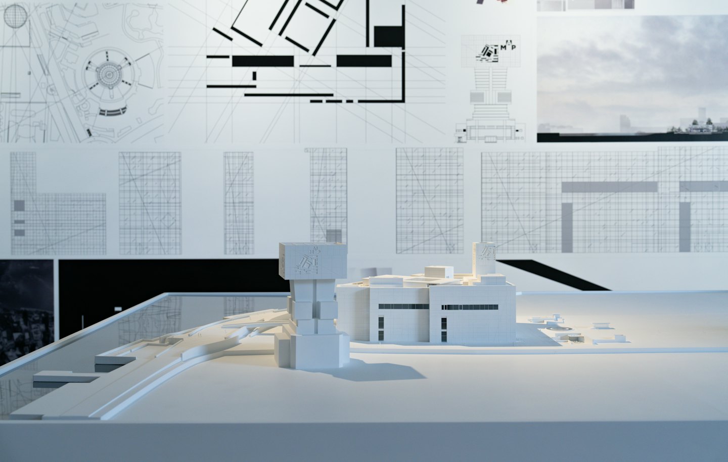 Maqueta de un moderno complejo de edificios sobre planos arquitectónicos.
