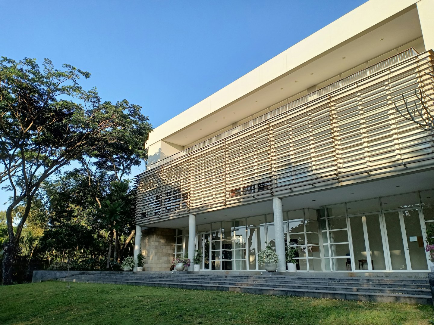 Edificio moderno con ventanas de cristal y césped delantero cuidado.