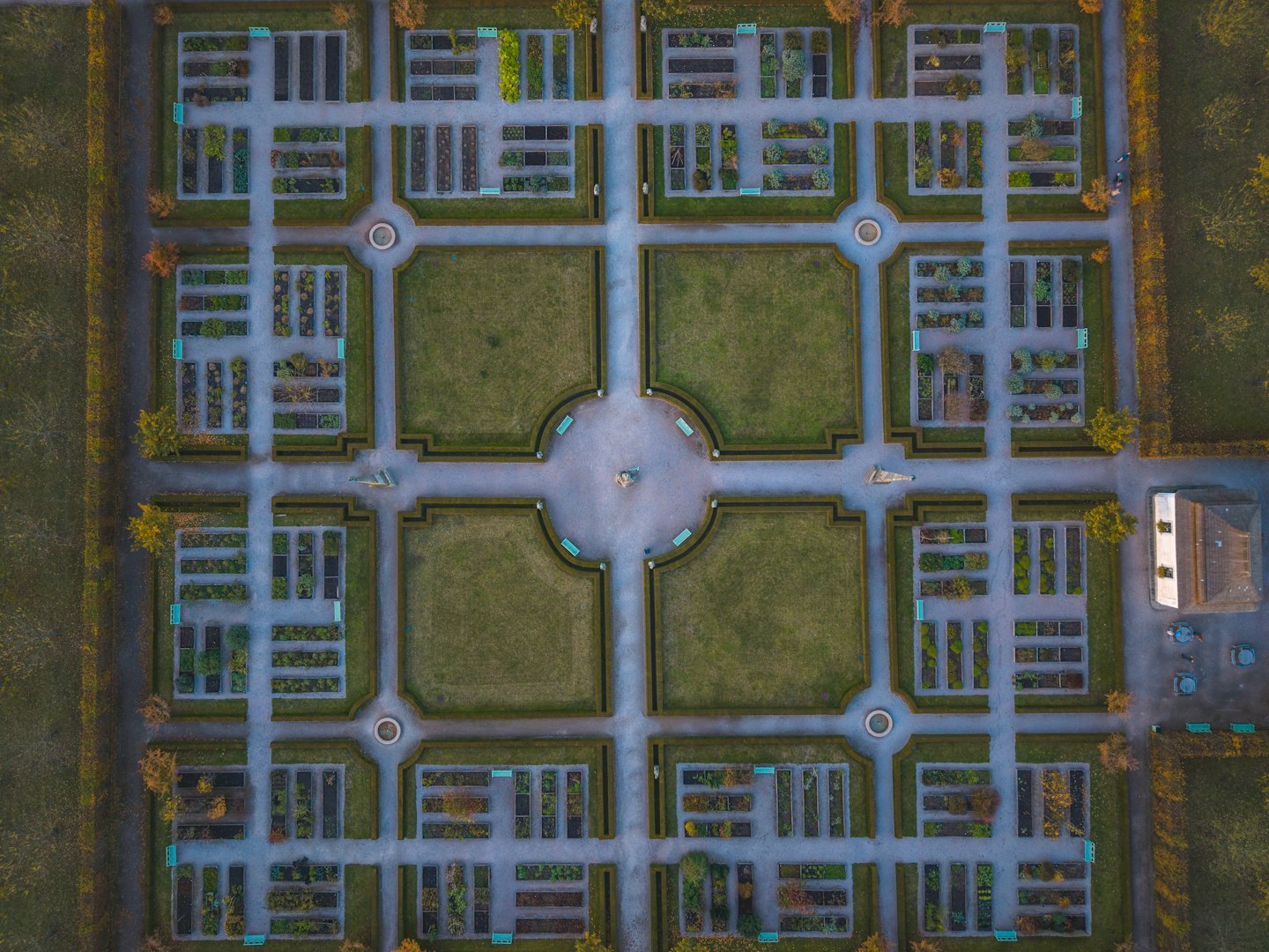 Jardín formal simétrico con setos cuidados y caminos de piedra gris.