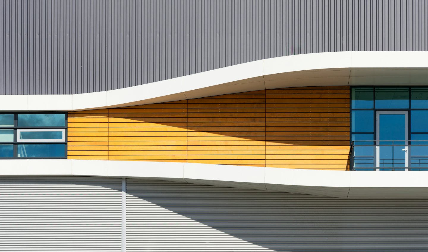 Exterior de edificio moderno con fachada de madera, metal y cristal.