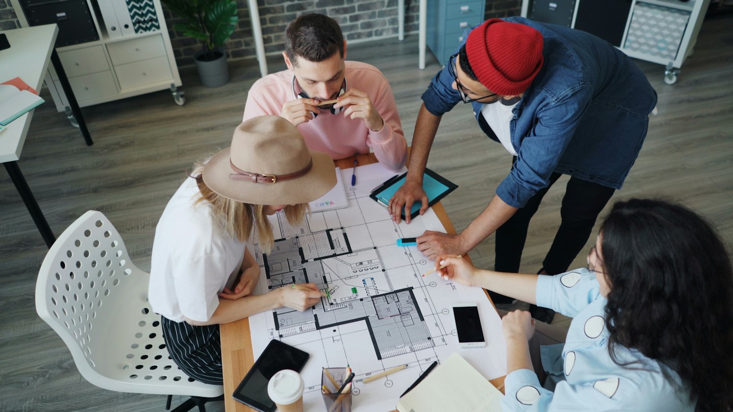 Profesionales colaboran en un plano arquitectónico sobre una mesa.