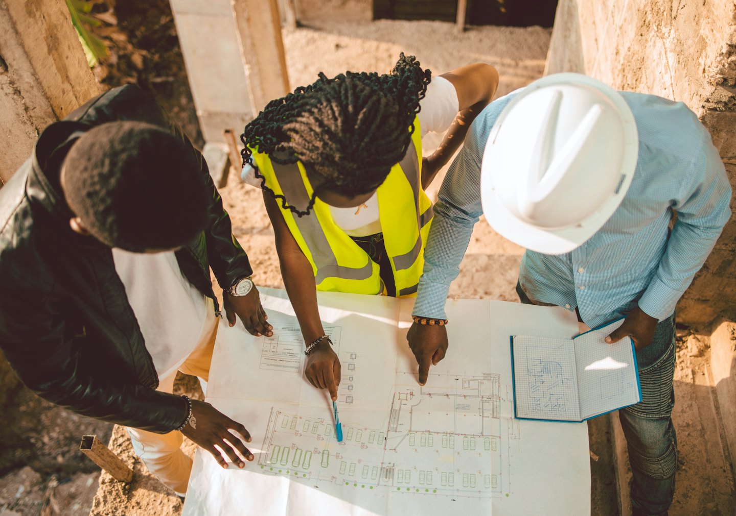 Tres profesionales de la construcción revisan planos en una obra de hormigón.